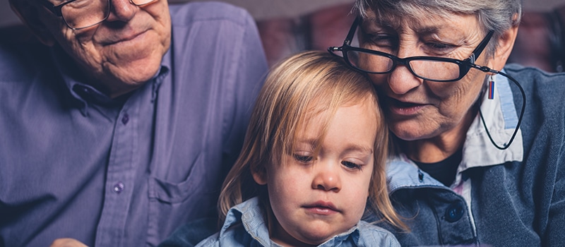 toddler with grandparents looking at a tablet