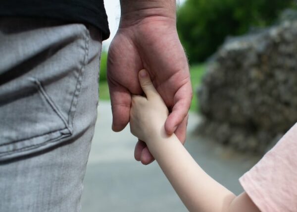 father with sole custody holds the child's hand